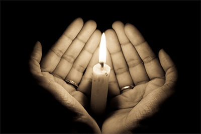 hands holding candle in the dark